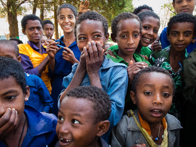 A chorus of curious faces gathers close, each expression holding its own story.