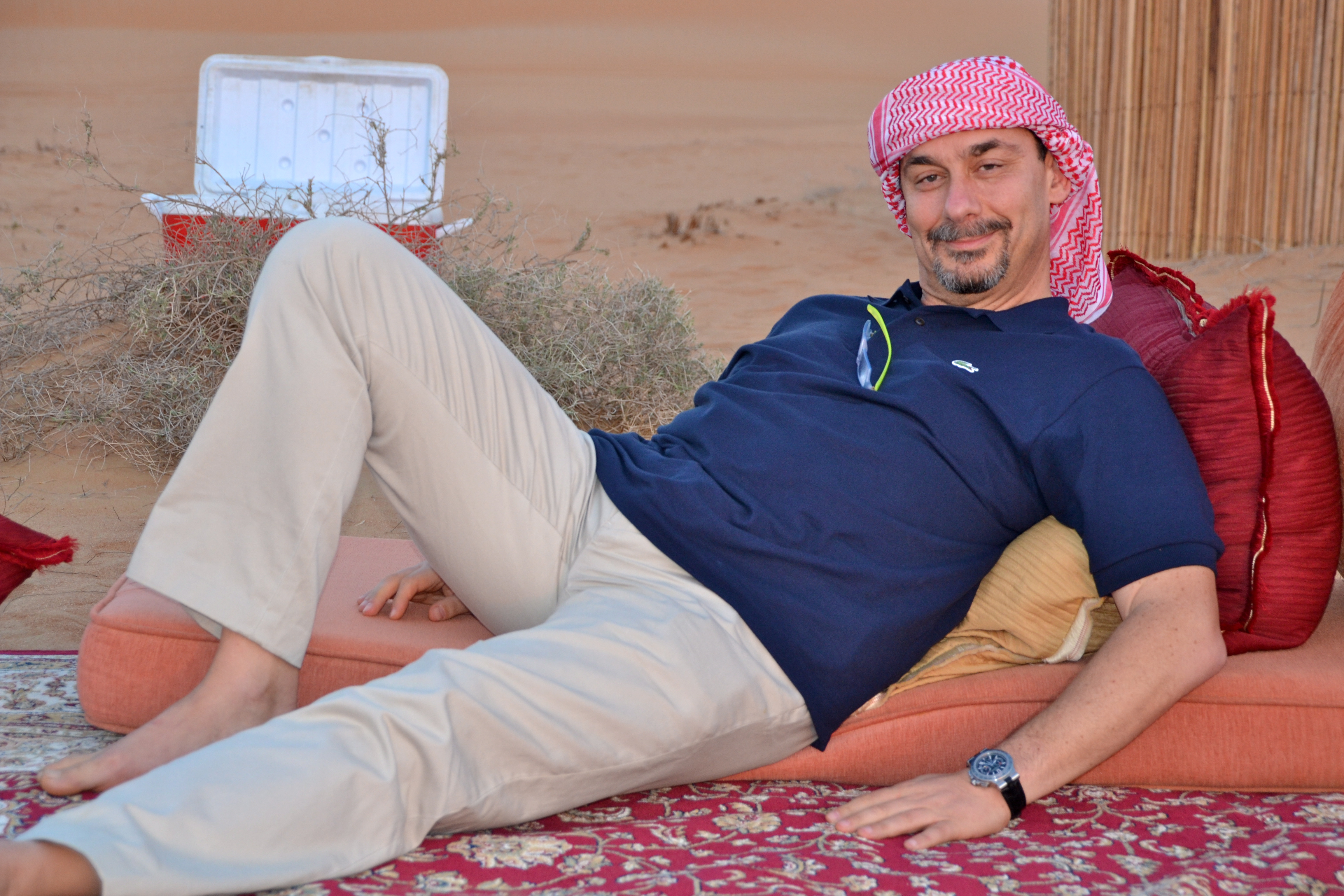 A quiet pause on cushions, with the desert camp softening into the background.