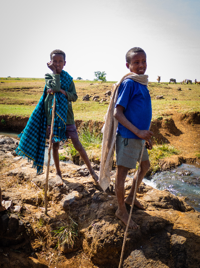 Two children pause above the water, bright cloth catching the open Tanzanian light.