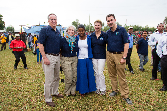 A field visit pauses for a portrait, with the day’s work continuing all around.